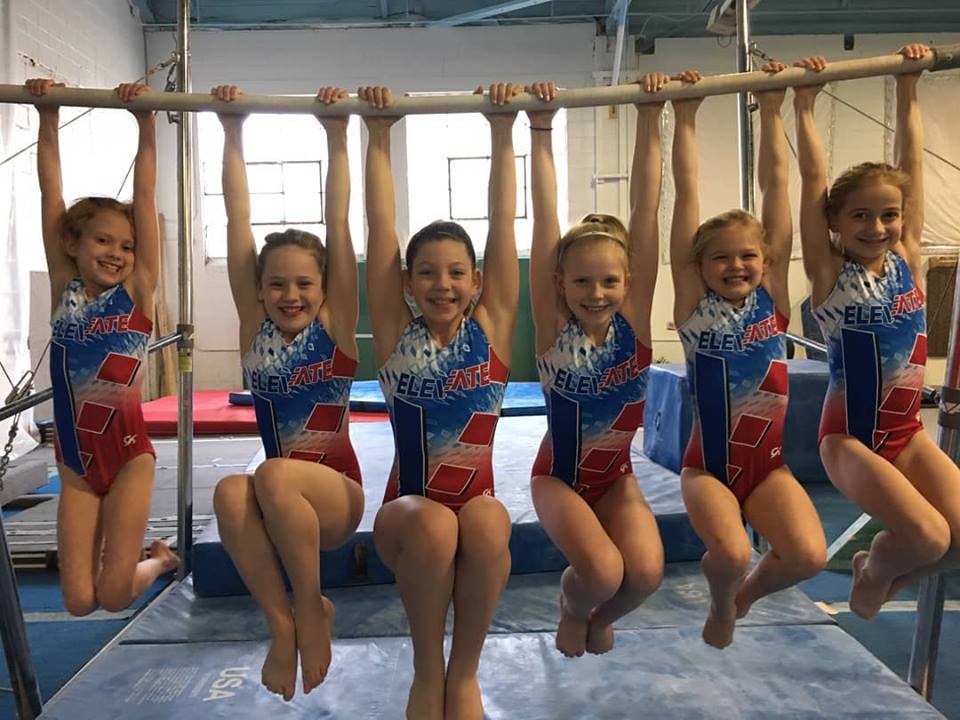 Startastics gymnasts hanging from the bar