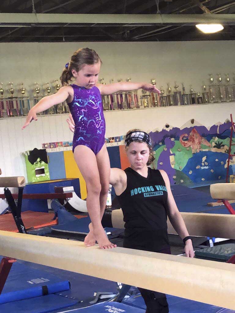 girl in purple tard balancing on a beam