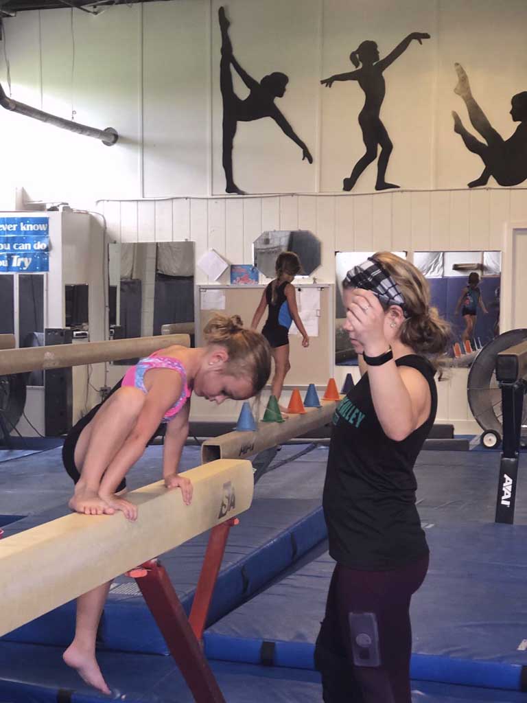 girl in black and pink tard balancing on a beam